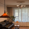Modern living room with a chandelier, pendant light, and large window.