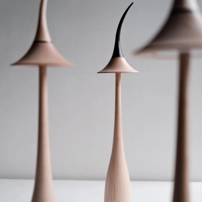 Three modern, tall ceramic lamps with pointed tops on a light gray background