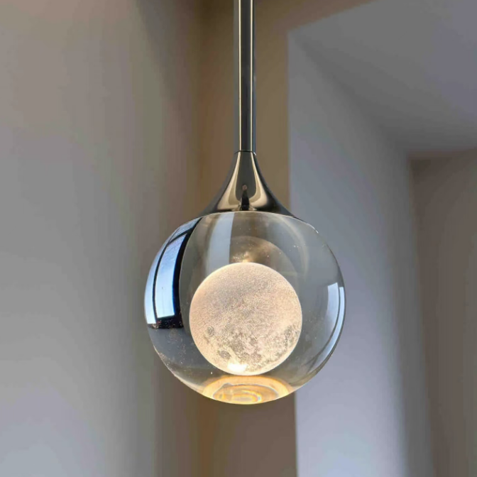 Modern pendant light with a glass shade and metallic fixture against a neutral background