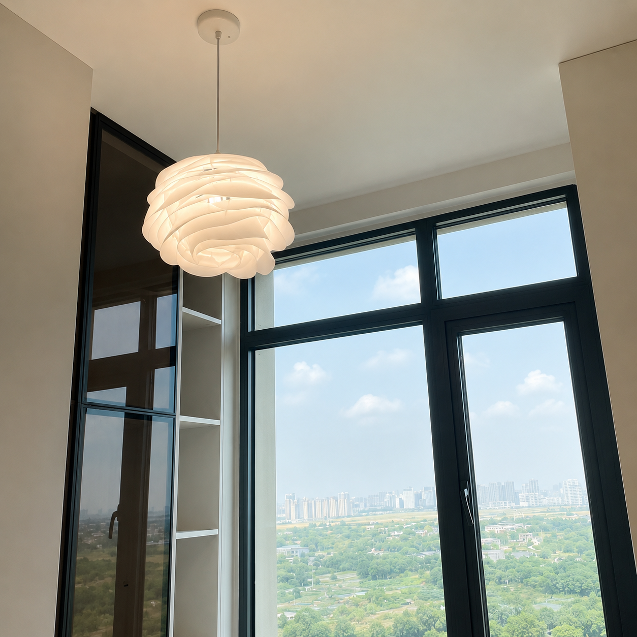 Modern pendant light fixture in a room with large windows showing a cityscape.