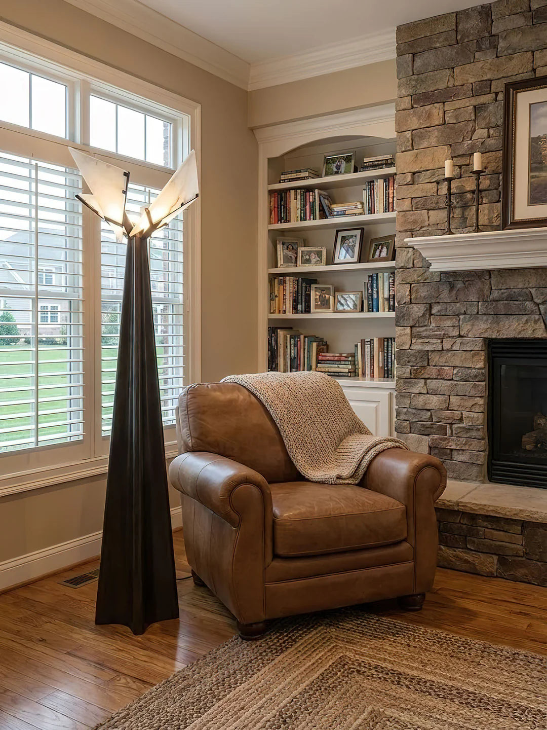 Cozy living room with a brown leather chair, stone fireplace, and bookshelf.