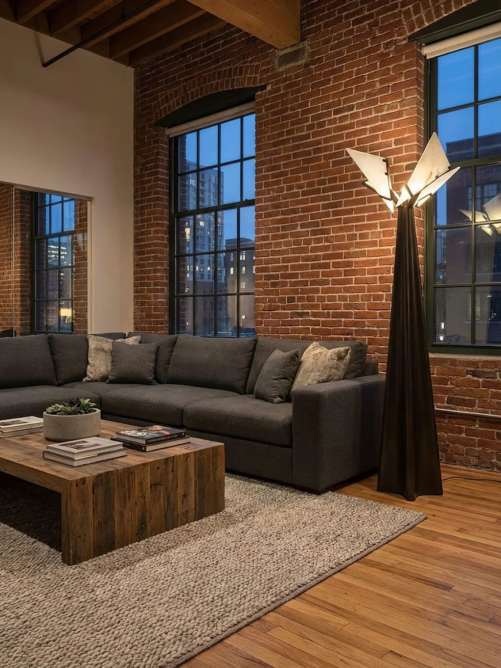 Modern living room with a sectional sofa, wooden coffee table, and brick wall.