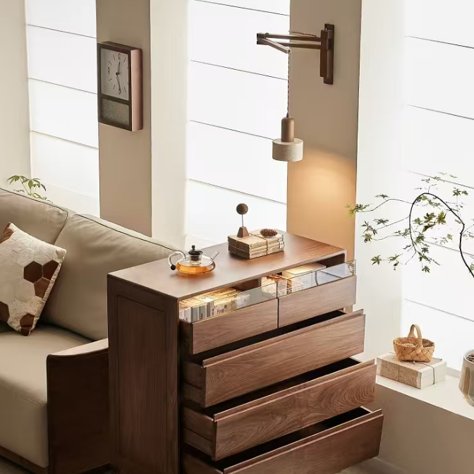 A mid-century modern wooden chest of drawers with three open drawers, styled in a warm, contemporary living room next to a beige sofa.