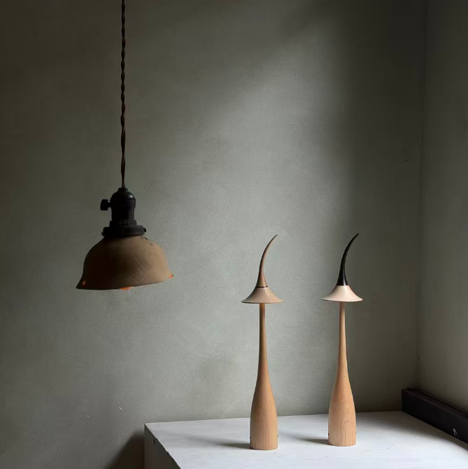 Pendant light and two wooden lamps on a white surface against a gray wall